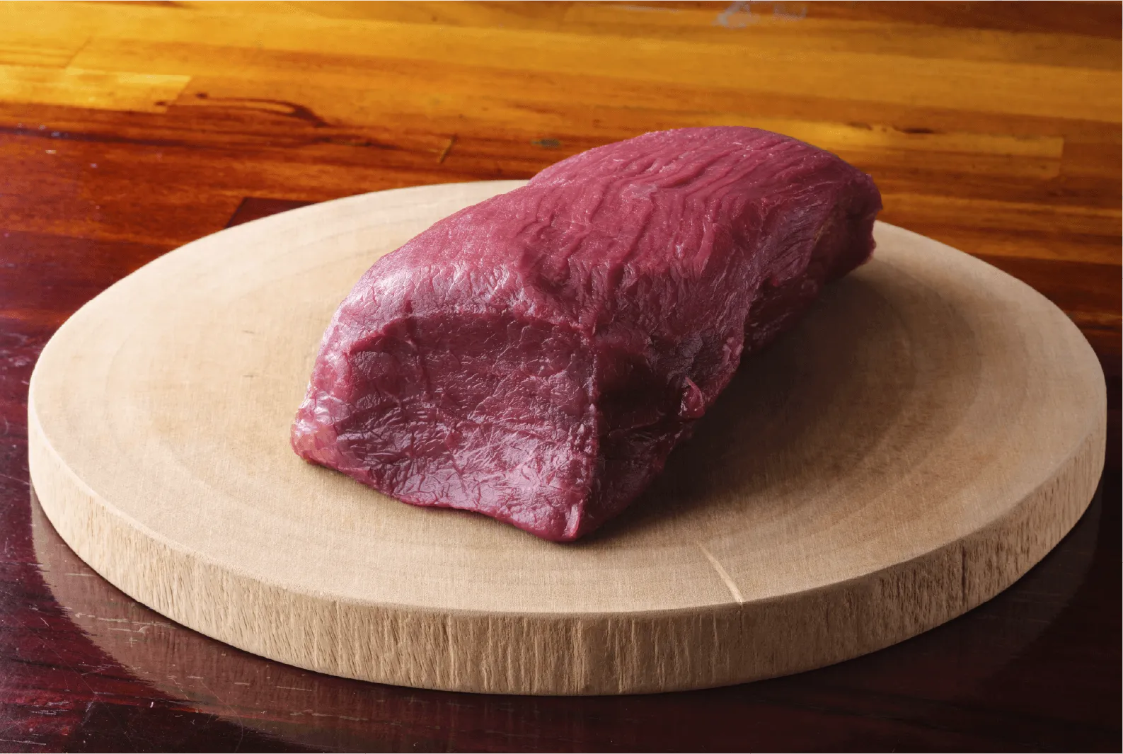 木製の板に乗っている鹿肉の写真